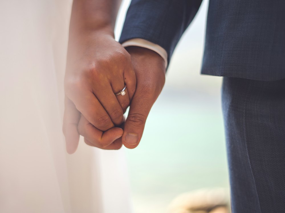 Close-up of a couple holding hands, wedding ring visible